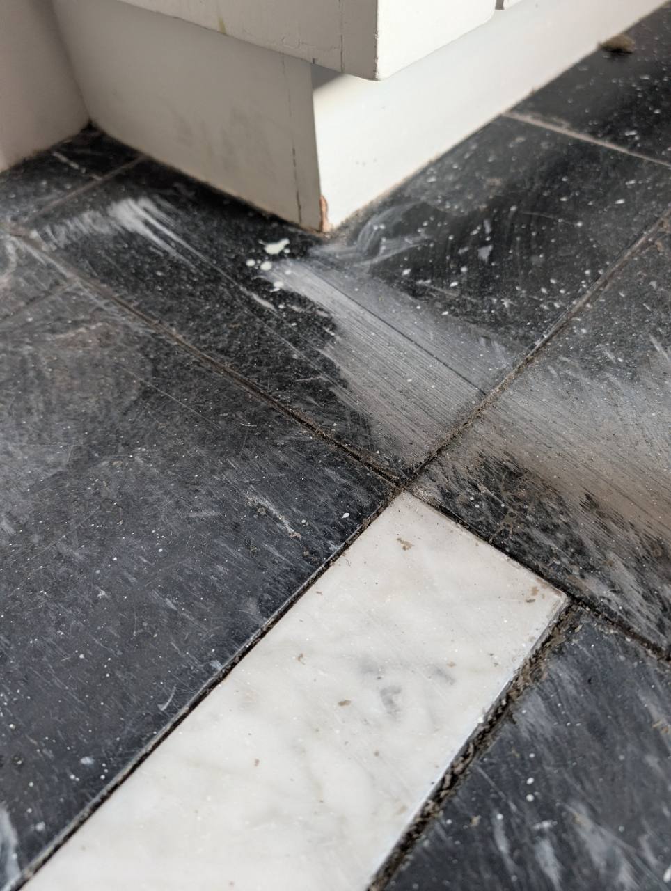 Close view of scratches and dull wear on Nero Marquina marble tiles