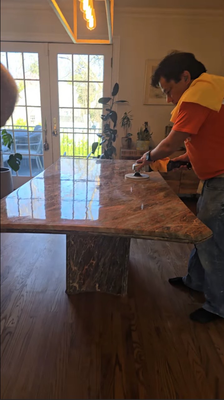 Final polishing of a large stone dining table in a protected apartment dining room