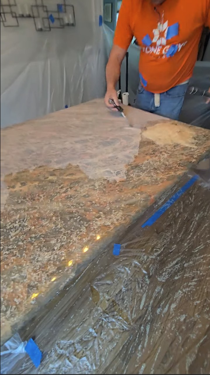 Technician removing a resin coating from a protected stone dining table in an NYC apartment